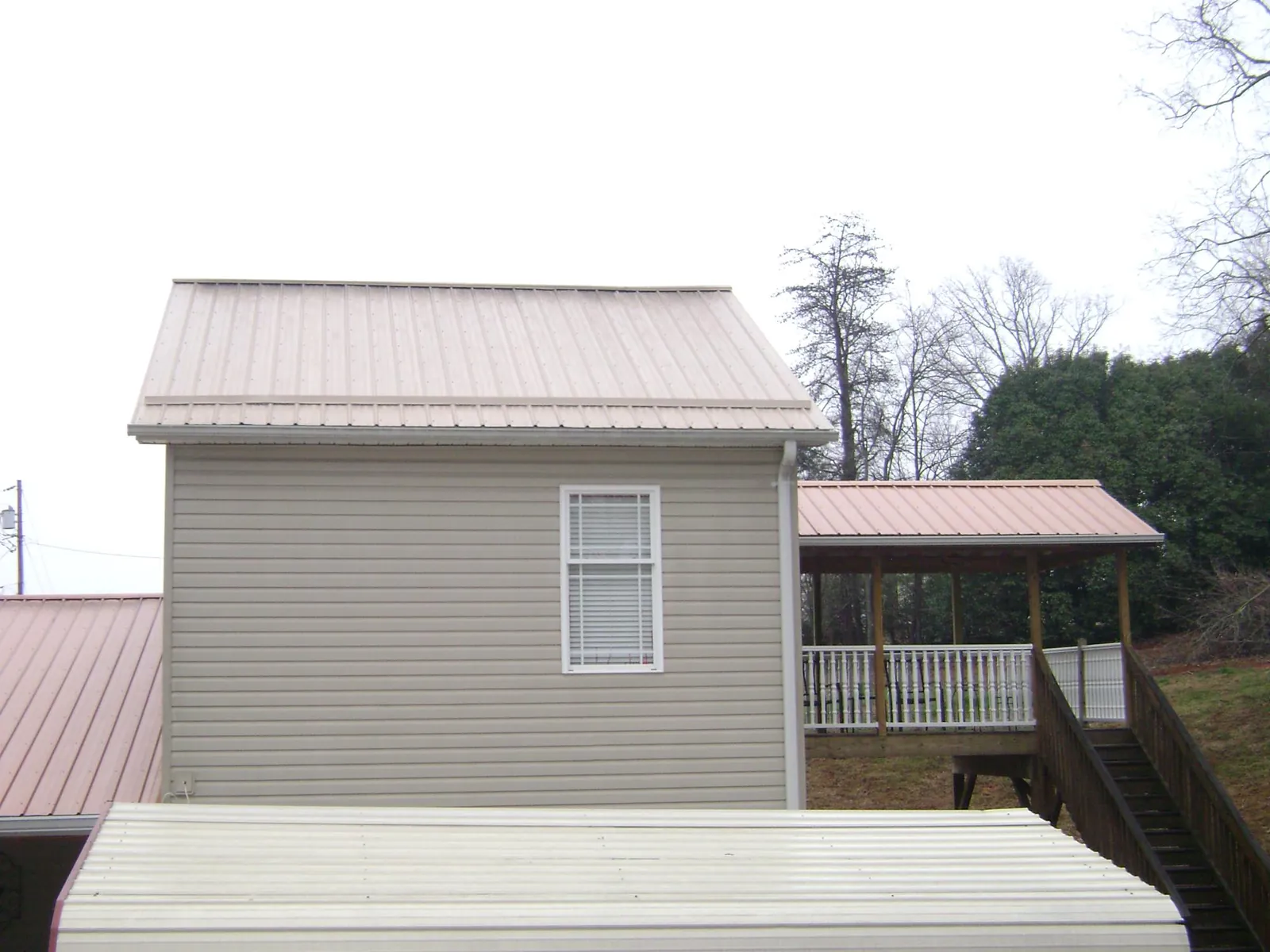Tan metal roofs on a two story addition and attached porch, from a Roof Replacement job in Glendale